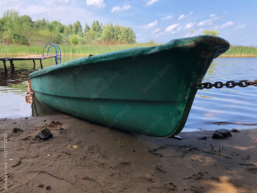 An old abandoned sunken river boat stands chained on the sandy river bank. An old abandoned sunken river boat stands chained on the sandy river bank.