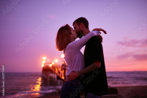 Caucasian couple in love kissing on the beach at sunset in Marbella, Spain. A guy and a girl in the popular resort of Marbella in Spain, Costa del Sol, Andalusia region, Malaga province. photo