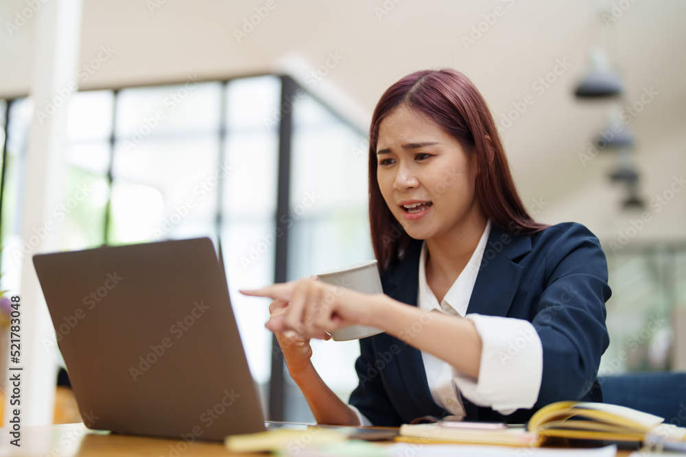 Asian businesswoman taking a coffee break while using a computer Asian businesswoman taking a coffee break while using a computer