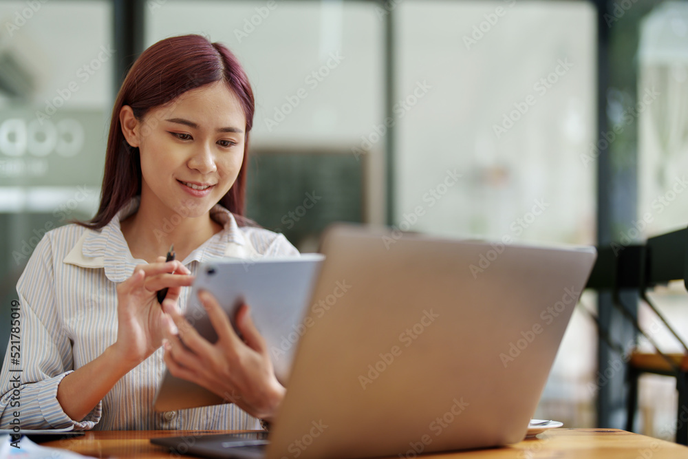 Portrait of an Asian female employee using a tablet computer at work. Portrait of an Asian female employee using a tablet computer at work.