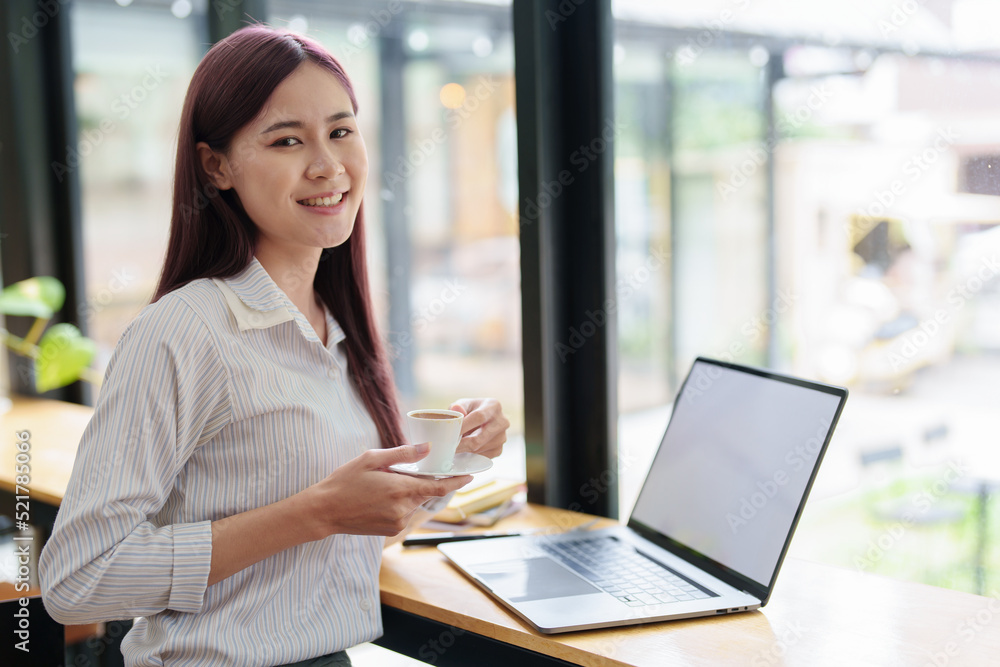 © Jirapong - Asian business woman drinking coffee and using computer in office © Jirapong - Asian business woman drinking coffee and using computer in office