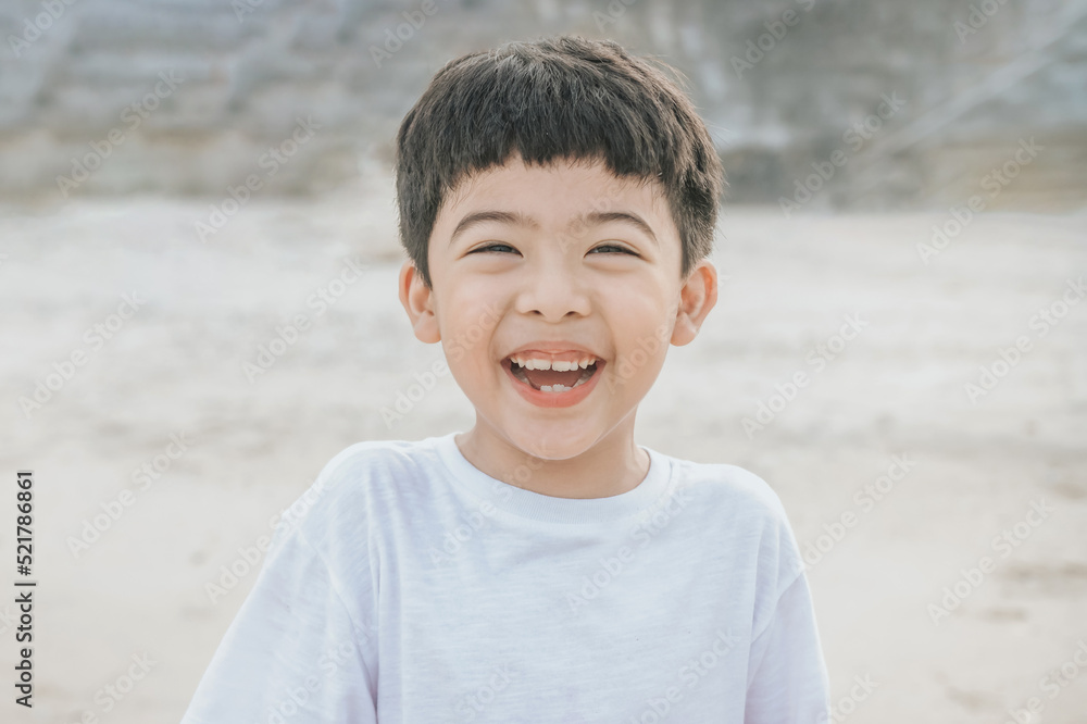 Portrait cute boy playing in the sandy beach, happy and Smiling and fun child. he wears a white shirt. Portrait cute boy playing in the sandy beach, happy and Smiling and fun child. he wears a white shirt.