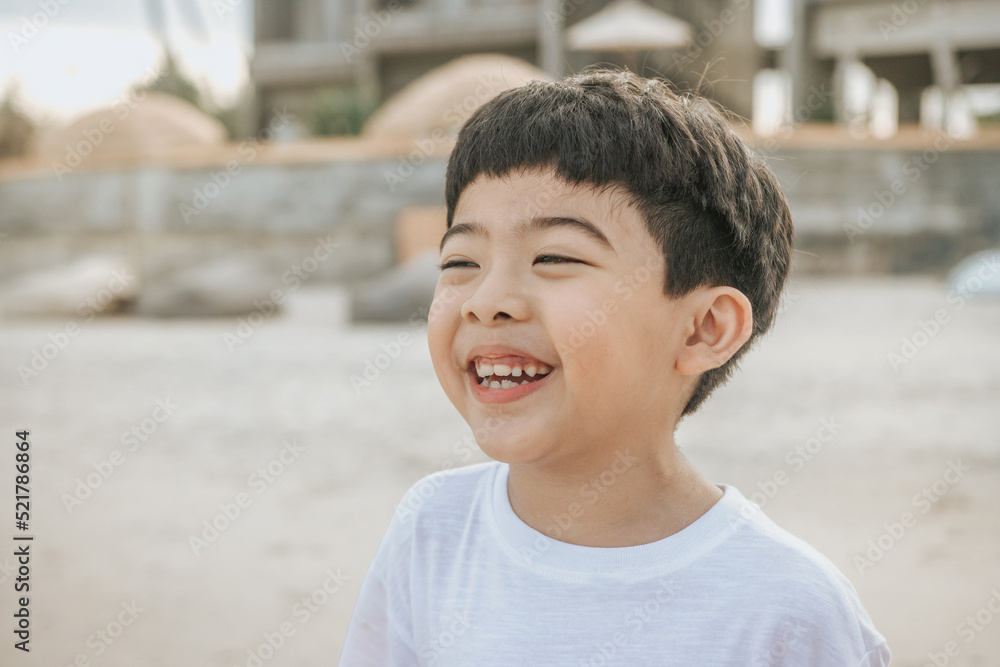 Portrait cute boy playing in the sandy beach, happy and Smiling and fun child. he wears a white shirt. Portrait cute boy playing in the sandy beach, happy and Smiling and fun child. he wears a white shirt.
