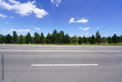 Fotografia The tarmac road is under blue sky and white clouds