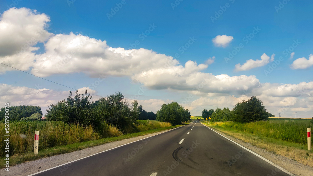 Asphalt road at the summer time. Blue sky with clouds. Travel and transportation concept background Asphalt road at the summer time. Blue sky with clouds. Travel and transportation concept background