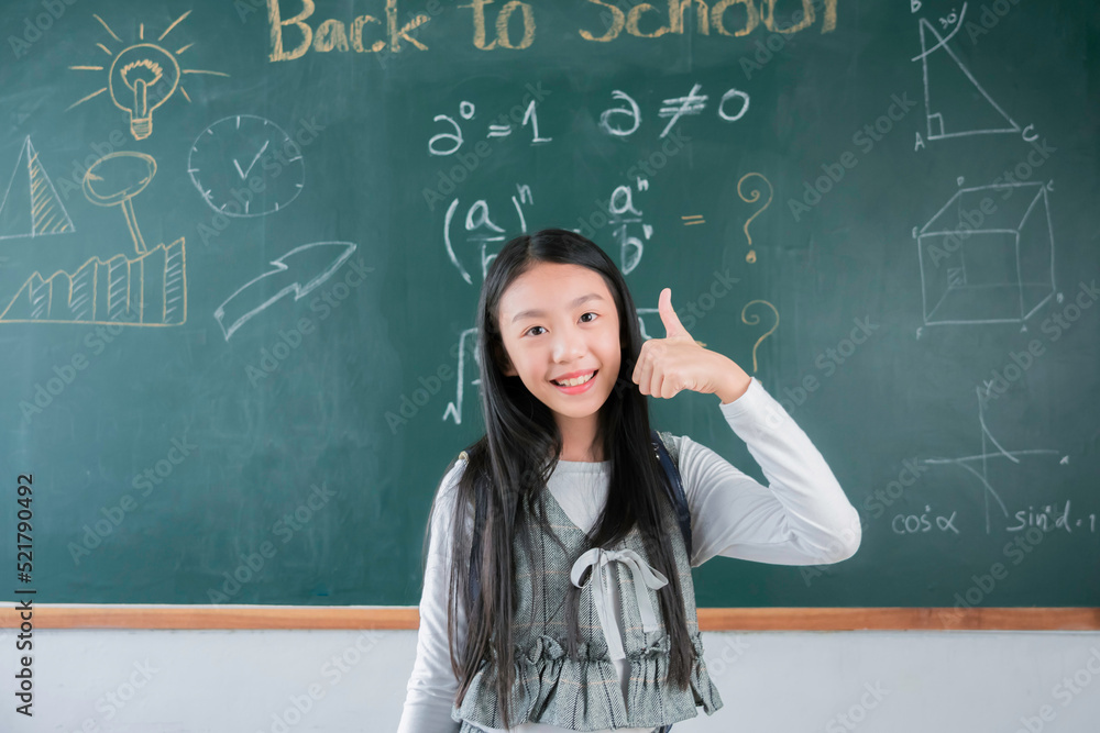Smiling asian girl student standing front blackboard in classroom school, Education learning study smart, Back to school concept.