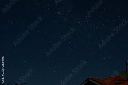 Fotografie Milky way galaxy with stars and space dust in the universe above a red roof
