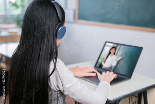 Rear view of asian girl student is learniing enlish online classroom listening teacher, Female teacher teaching vocabulary by laptop computer at home using technology. photo