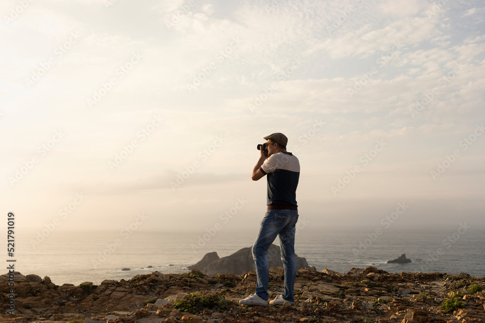 Travel content creator photographer taking pictures of beautiful sea sunset scenery from cliffs for blog, social media. lifestyle freelance photographer concept adventure summer travel outdoors