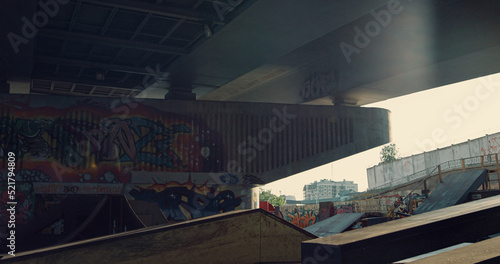 Skate park with artistic graffiti on wall. Empty skate park with rail and ramp.