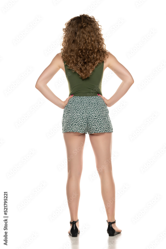 A woman in a summer shorts and shirt on a white, Back view A woman in a summer shorts and shirt on a white, Back view