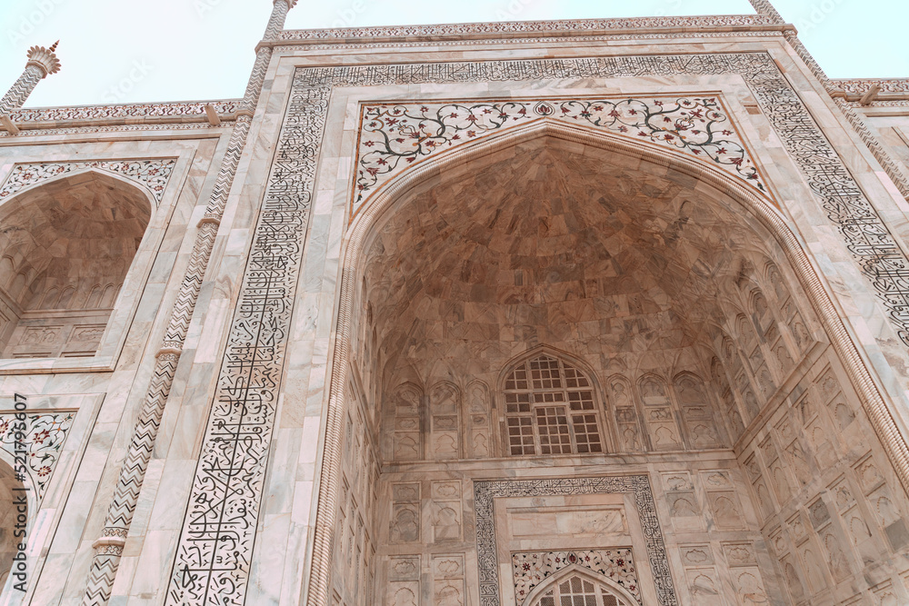 Taj Mahal, islamic ivory-white marble mausoleum, close-up on a historic ornate facade.