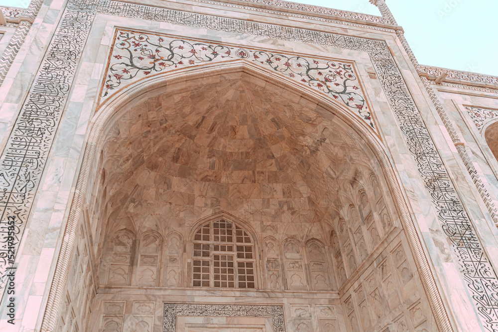 Taj Mahal, islamic ivory-white marble mausoleum, close-up on a historic ornate facade.
