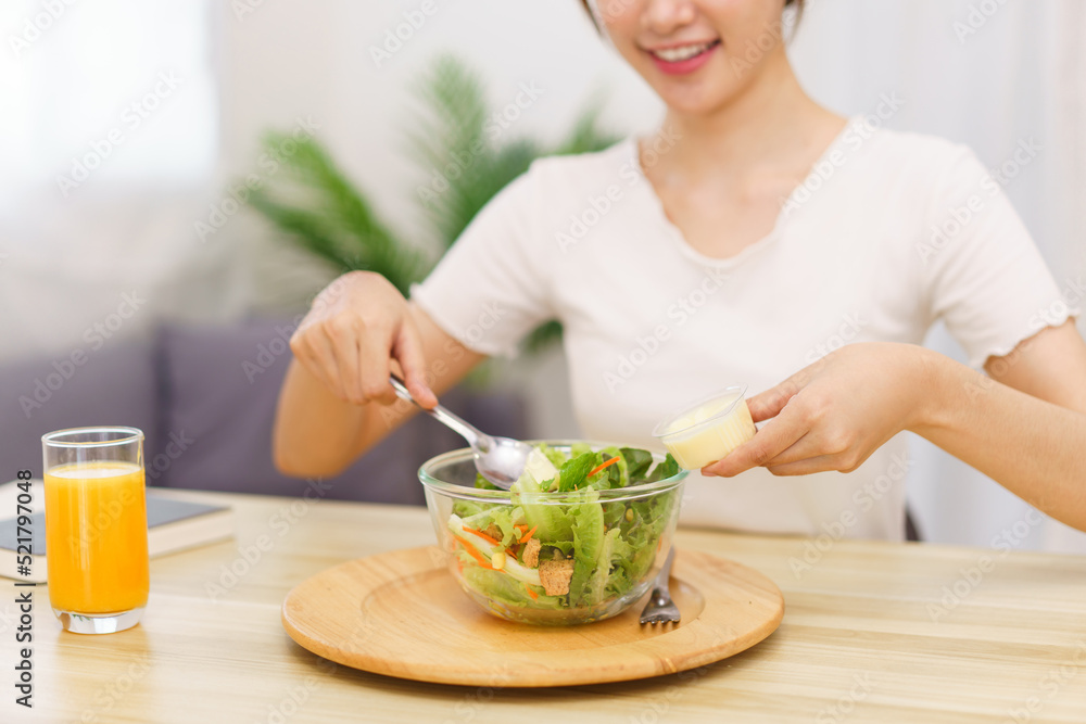 Lifestyle in living room concept, Asian woman using spoon to ladle salad dressing into salad bowl Lifestyle in living room concept, Asian woman using spoon to ladle salad dressing into salad bowl