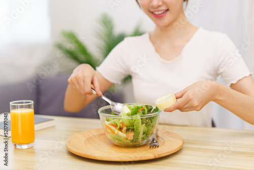 Lifestyle in living room concept  Asian woman using spoon to ladle salad dressing into salad bowl