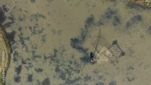 Fisherman catches fish with a large net in a drained pond, top view