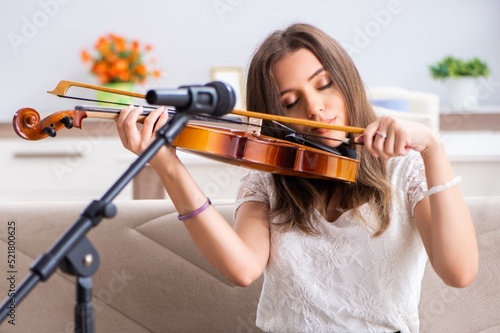 Female beautiful musician playing violin at home