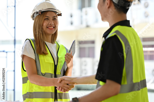 Two Asian Engineers or Architects shaking hands at construction site.