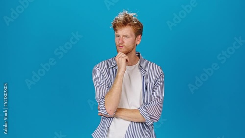 Pensive redhead man touches beard listening to companion photo