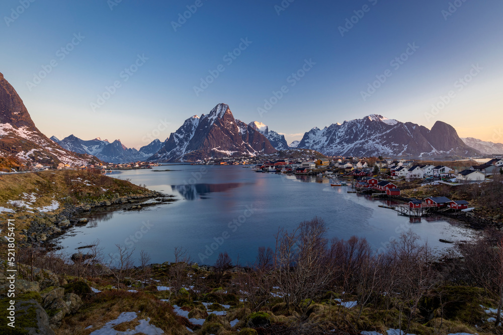 norwegian landscape with sea on the foreground and snowy mountains on the background, lofoten sunny weather with blue sky. Reine