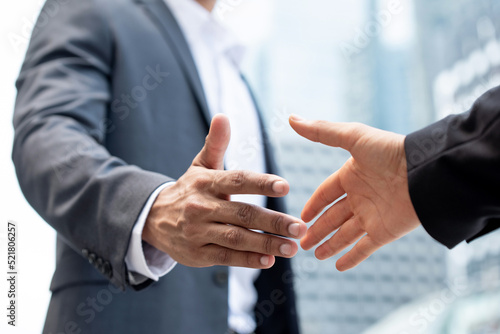Businessmen making handshake outdoors in city office building background for merger and acquisition concept photo