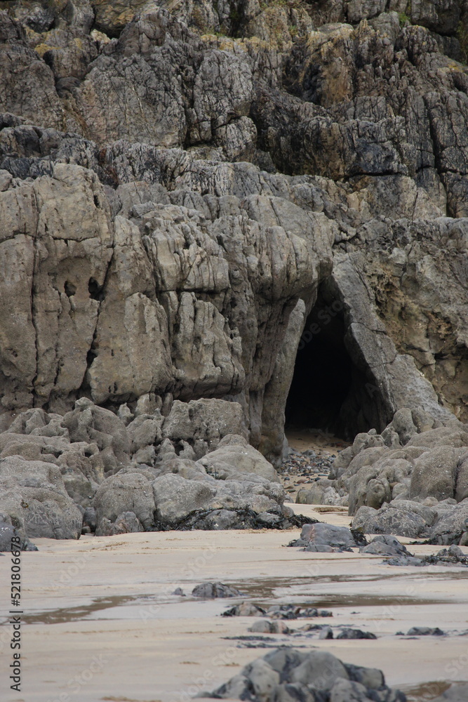 A photograph of an eerie cave entrance on a beach