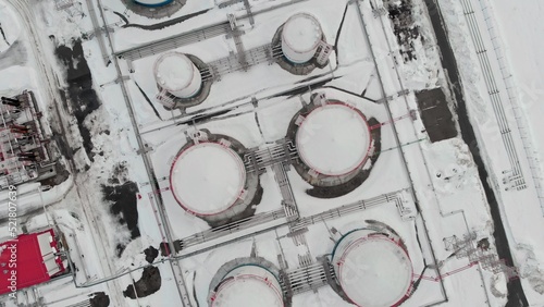 Drone flies over snow-covered oil tanks. Oil storage tanks for the winter period. A strategic oil reserve in a crisis and a sharp increase in prices due to wars and sanctions.