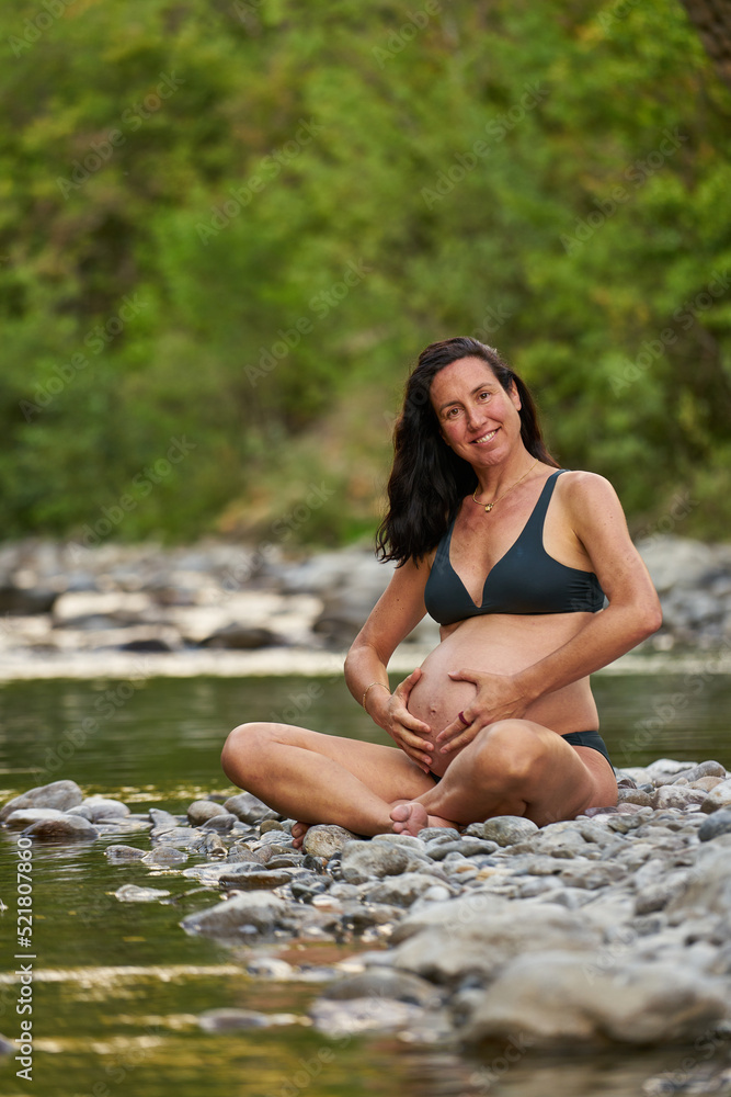 Relaxed pregnant woman in the nature, enjoying a beautiful spot on a river shore. Relaxed pregnant woman in the nature, enjoying a beautiful spot on a river shore.