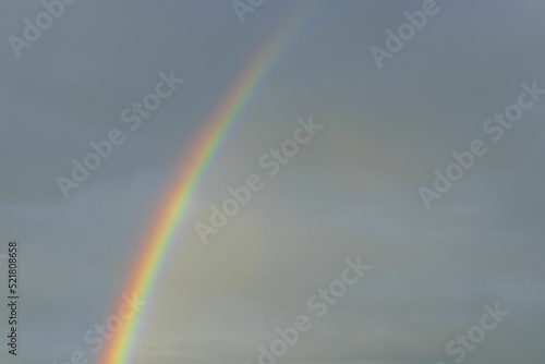 Close up view of rainbow in cloudy evening summer sky. Sweden.