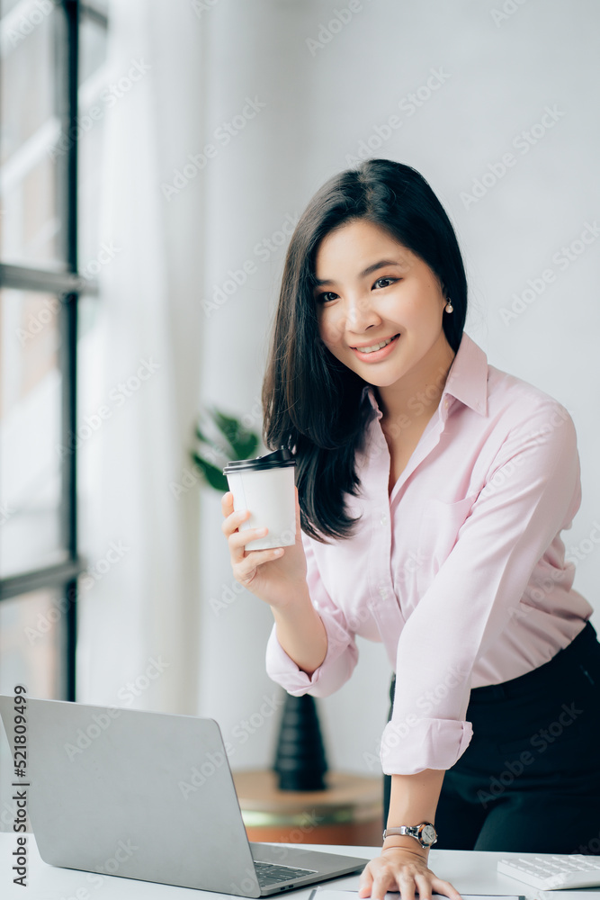 Charming Asian businesswoman working with a laptop at the office. Looking at camera Charming Asian businesswoman working with a laptop at the office. Looking at camera