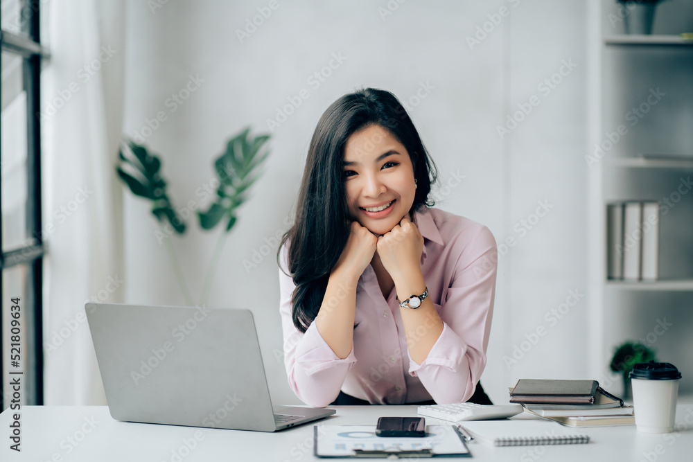 Charming Asian businesswoman working with a laptop at the office. Looking at camera Charming Asian businesswoman working with a laptop at the office. Looking at camera