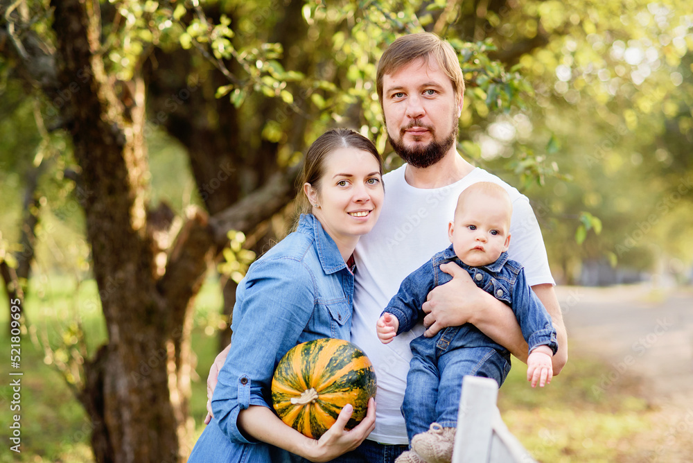 Portrait of Happy family hugging and spending time together outside in green nature. Young mother and father with little baby in garden. Apple harvest and picking on farm in autumn. Portrait of Happy family hugging and spending time together outside in green nature. Young mother and father with little baby in garden. Apple harvest and picking on farm in autumn.