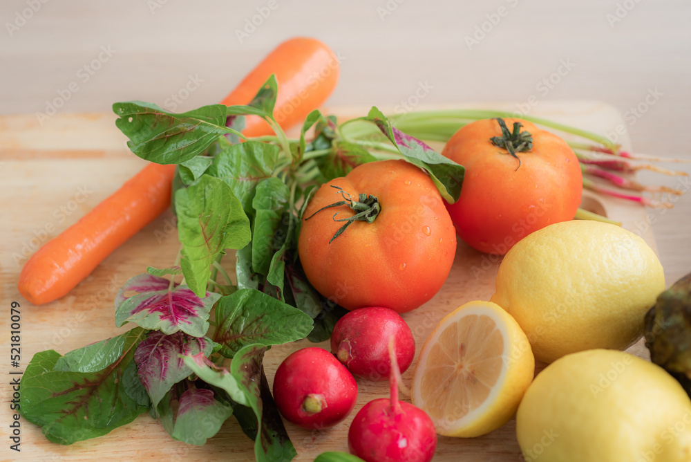 Top view of tomatoes, spinach(red amaranth), radish, carrot and lemon placed on cutting board. As a organic raw material for making salads on the kitchen table. Top view of tomatoes, spinach(red amaranth), radish, carrot and lemon placed on cutting board. As a organic raw material for making salads on the kitchen table.