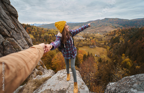 Couple travelers holding hands, Woman wanting her man to follow her, pointing to the autumn mountains view. Popular tourist place in Ukraine, Tustan National Park photo