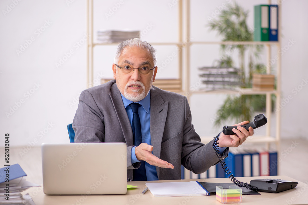 Old male employee working at workplace Old male employee working at workplace