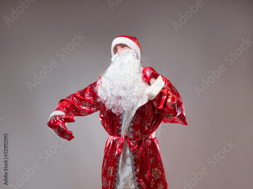Santa Claus is a traditional Russian grandfather in a red caftan with a bag of gifts. A man in a New Year's costume. Children's holiday, New Year's gifts for everyone photo