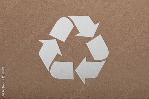 Sheet of cardboard with cutout recycling symbol on white background, top view
