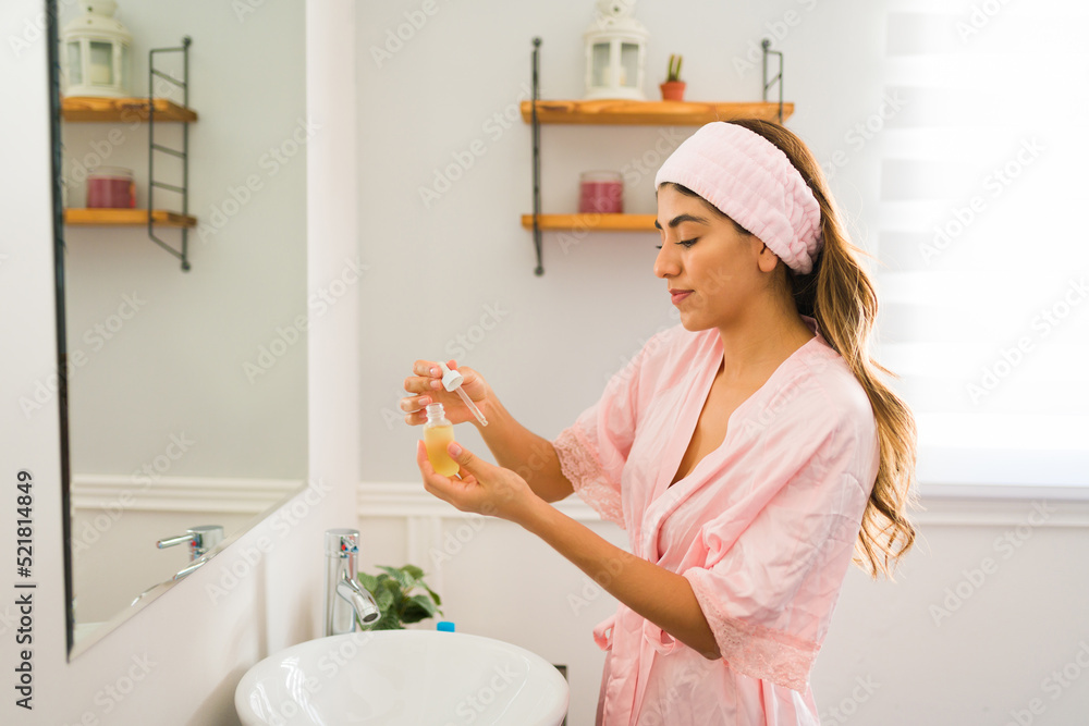 Latin woman putting a moisturizing oil on her face Latin woman putting a moisturizing oil on her face