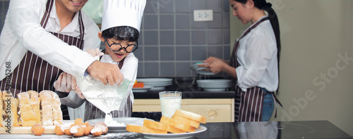 Cute asian boy with parent wearing chef hat  apron preparing for baking dough in kitchen at home