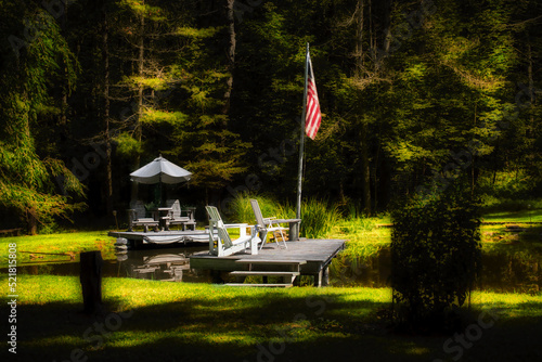 Two docks on a small private pond in Upstate NY are very inviting this summer evening.  American flag at the end of the dock with comfortable chairs around it.