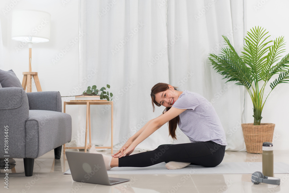 Yoga exercise concept, Young Asian woman is stretching leg and arm while doing yoga online at home Yoga exercise concept, Young Asian woman is stretching leg and arm while doing yoga online at home