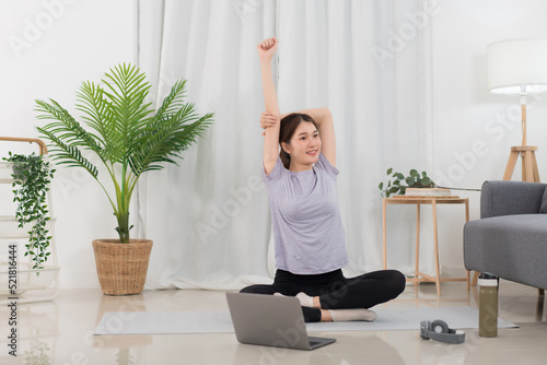 Fototapeta Naklejka Na Ścianę i Meble -  Yoga exercise concept, Young Asian woman stretching arms before workout with yoga training online