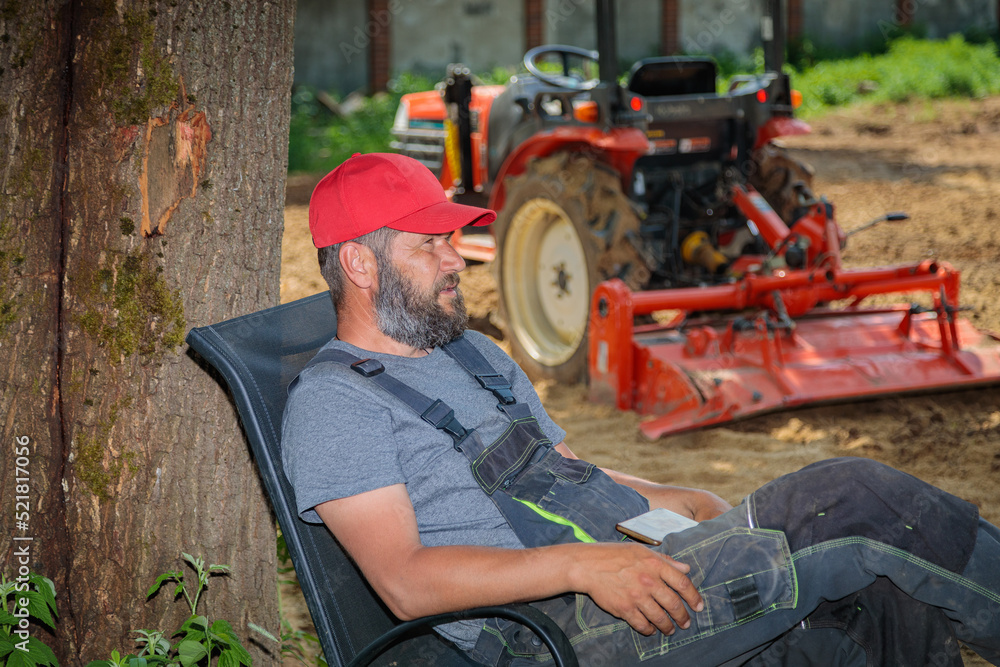 Tractor driver rests in the shade of a tree after plowing the land. Agricultural work on the site