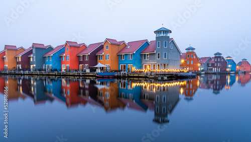 A overview of the colourful houses at Reitdiephaven during Chrismas Time. The houses have a nice reflection in the water that has turned blue during the blue hour.