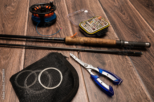 A collection  of fly fishing paraphernalia on a dark wood background