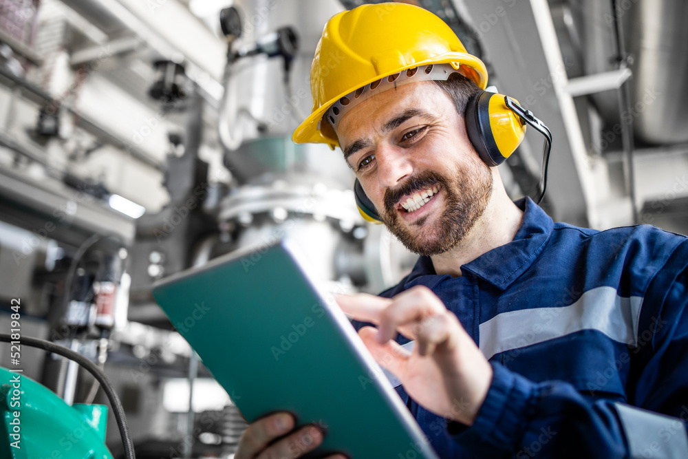 Smiling caucasian worker checking analysis and production on his computer in refinery factory. Smiling caucasian worker checking analysis and production on his computer in refinery factory.