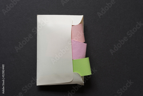 paper envelope stuffed with folded paper strips (or paper object isolated on a dark background) © eugen