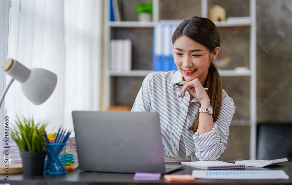 Confident successful businesswoman, freelancer or employee, sits at her work desk at home or in the office, uses a laptop, chats with colleagues, responds to emails, browses the Internet Confident successful businesswoman, freelancer or employee, sits at her work desk at home or in the office, uses a laptop, chats with colleagues, responds to emails, browses the Internet