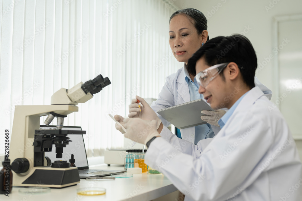 biochemical research scientist team working with microscope for vaccine development in pharmaceutical research labolatory. biochemical research scientist team working with microscope for vaccine development in pharmaceutical research labolatory.