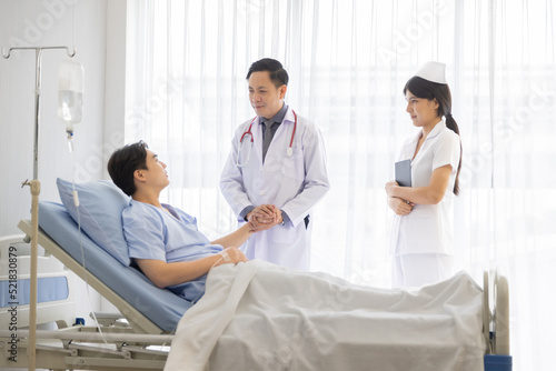 Professional male doctor and nurse caring visiting encourage male patient at hospital